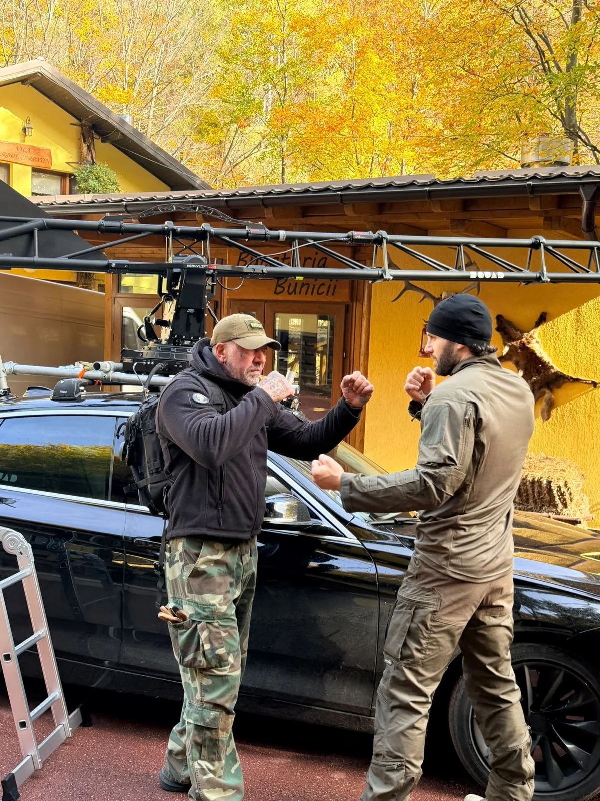 Fight rehearsal beside a vehicle and filming equipment